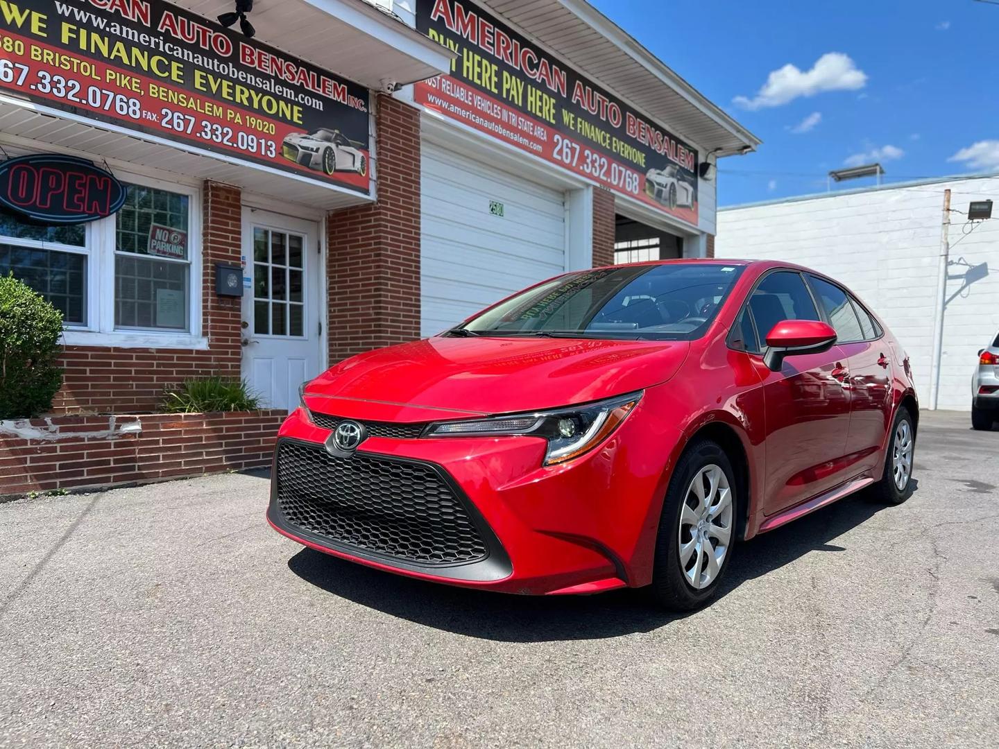 A vibrant red 2020 Toyota Corolla with a sleek exterior, featuring four doors and black interior, parked in a modern setting, showcasing its stylish design.