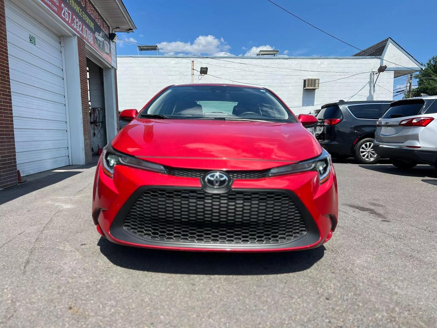 A vibrant red 2020 Toyota Corolla with a sleek exterior, featuring four doors and black interior, parked in a modern setting, showcasing its stylish design.