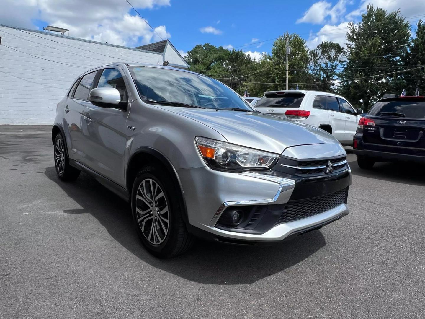 2018 Mitsubishi Outlander Sport in a scenic outdoor setting, highlighting its sleek design, bold grille, and compact SUV styling.