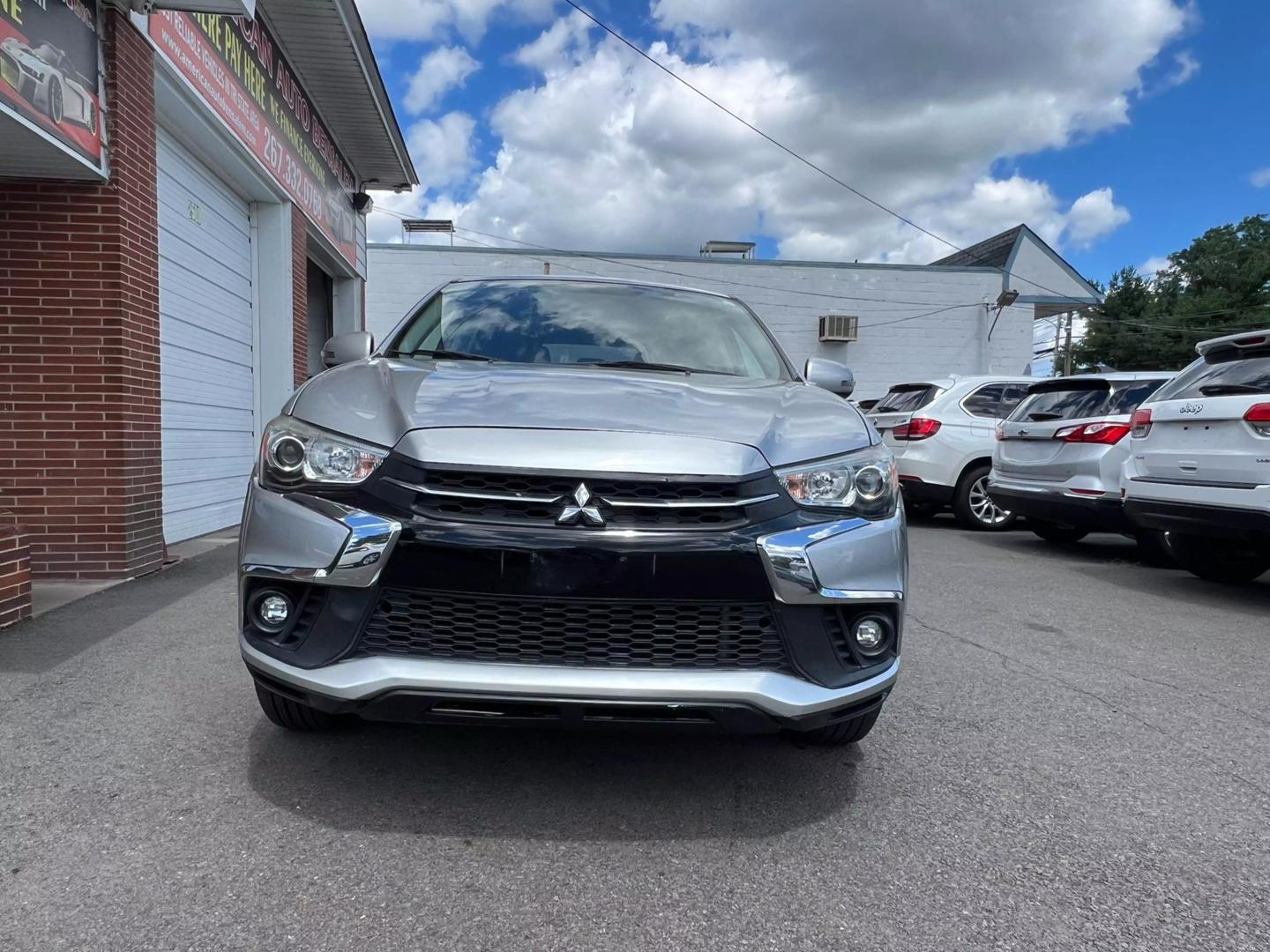 2018 Mitsubishi Outlander Sport in a scenic outdoor setting, highlighting its sleek design, bold grille, and compact SUV styling.