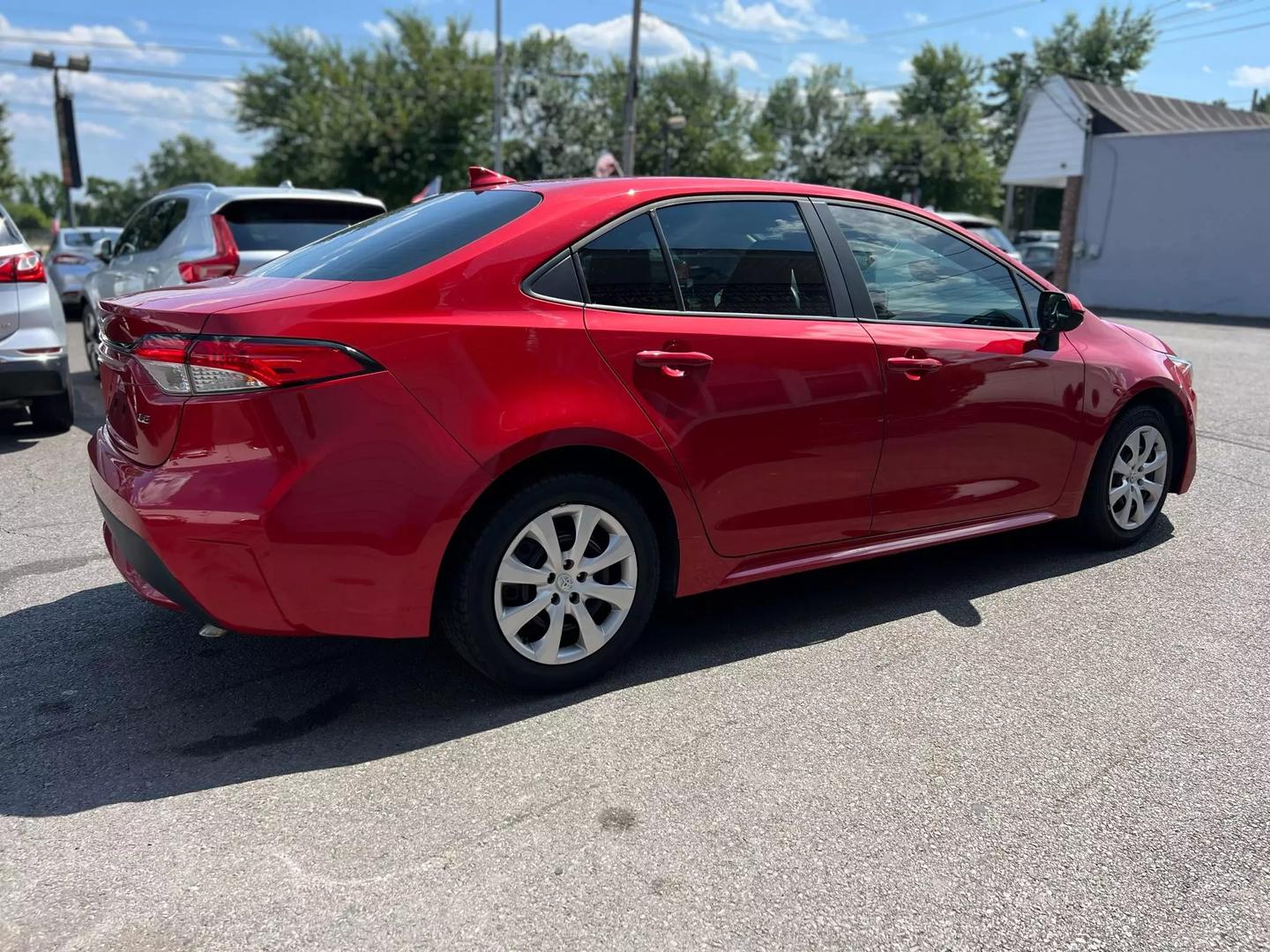 A vibrant red 2020 Toyota Corolla with a sleek exterior, featuring four doors and black interior, parked in a modern setting, showcasing its stylish design.