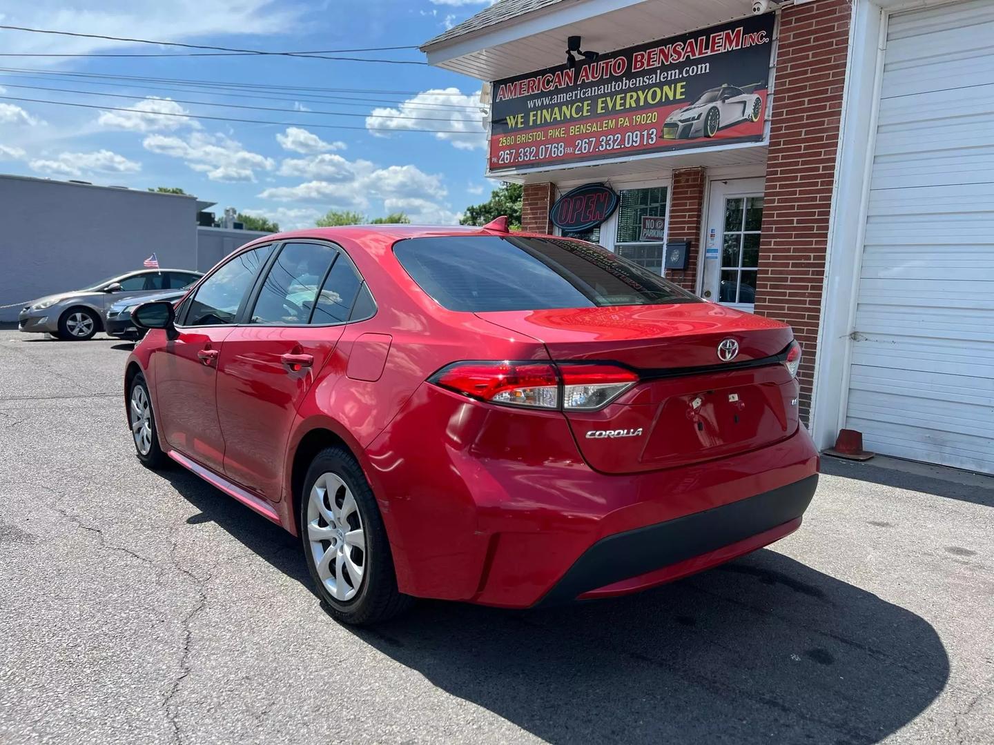 A vibrant red 2020 Toyota Corolla with a sleek exterior, featuring four doors and black interior, parked in a modern setting, showcasing its stylish design.