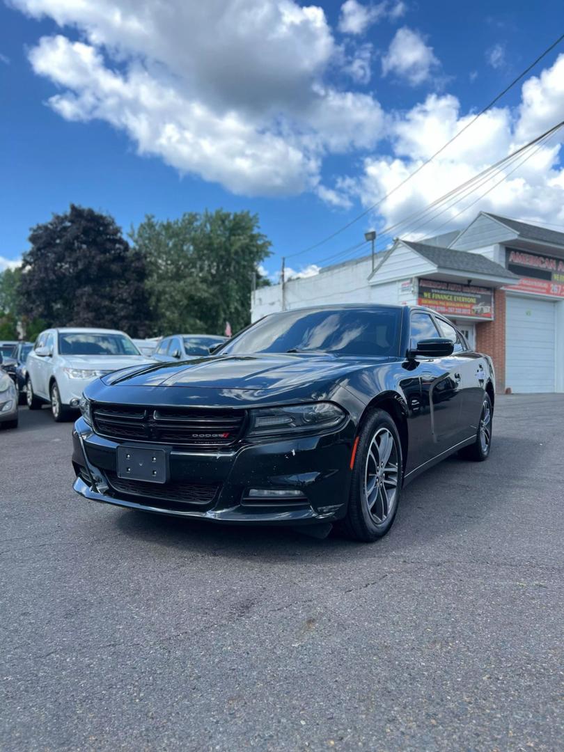 A sleek black 2019 Dodge Charger parked on a scenic road, showcasing its aggressive design and sporty silhouette under clear blue skies.