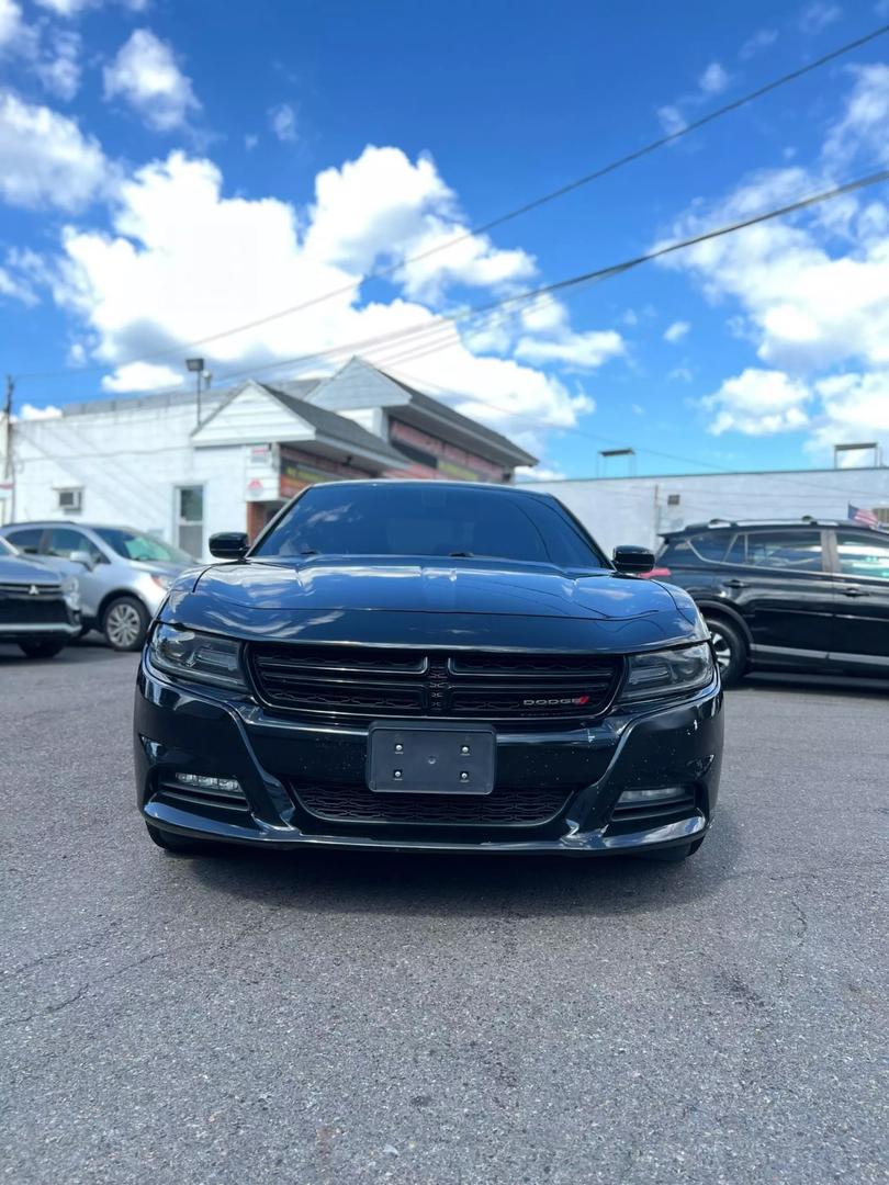 A sleek black 2019 Dodge Charger parked on a scenic road, showcasing its aggressive design and sporty silhouette under clear blue skies.