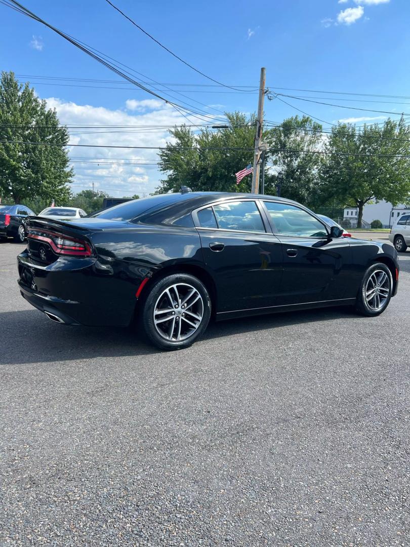 A sleek black 2019 Dodge Charger parked on a scenic road, showcasing its aggressive design and sporty silhouette under clear blue skies.