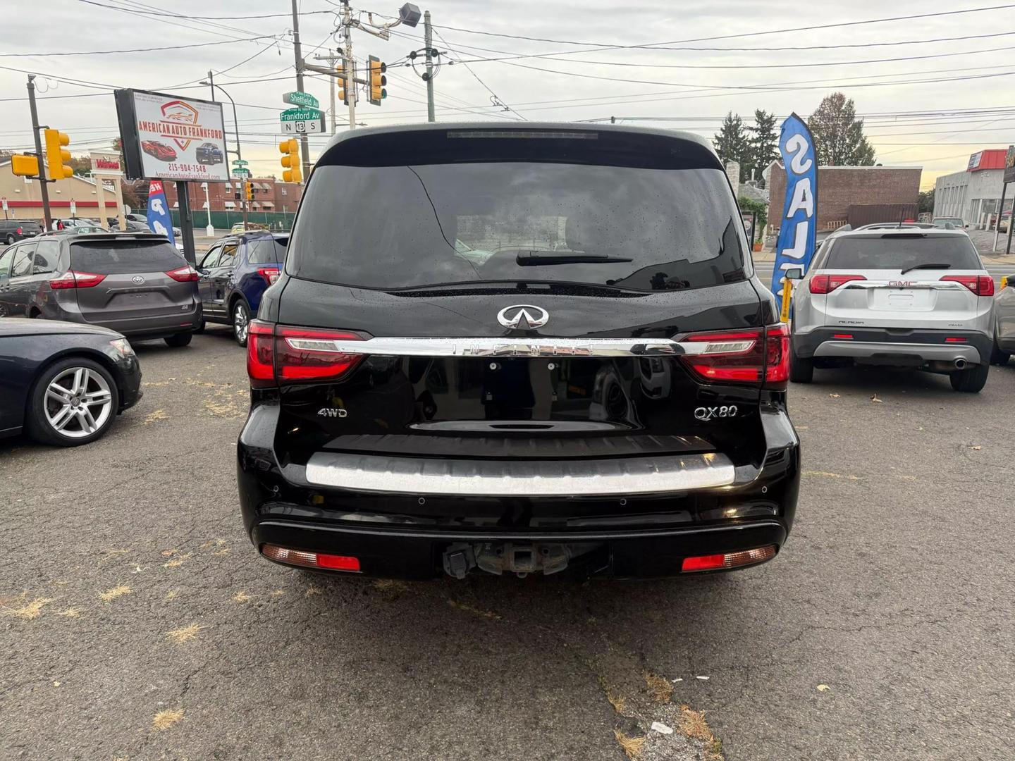 2021 INFINITI QX80 cruising a scenic mountain road, bold grille, sleek design, and LED headlights glowing at sunset.